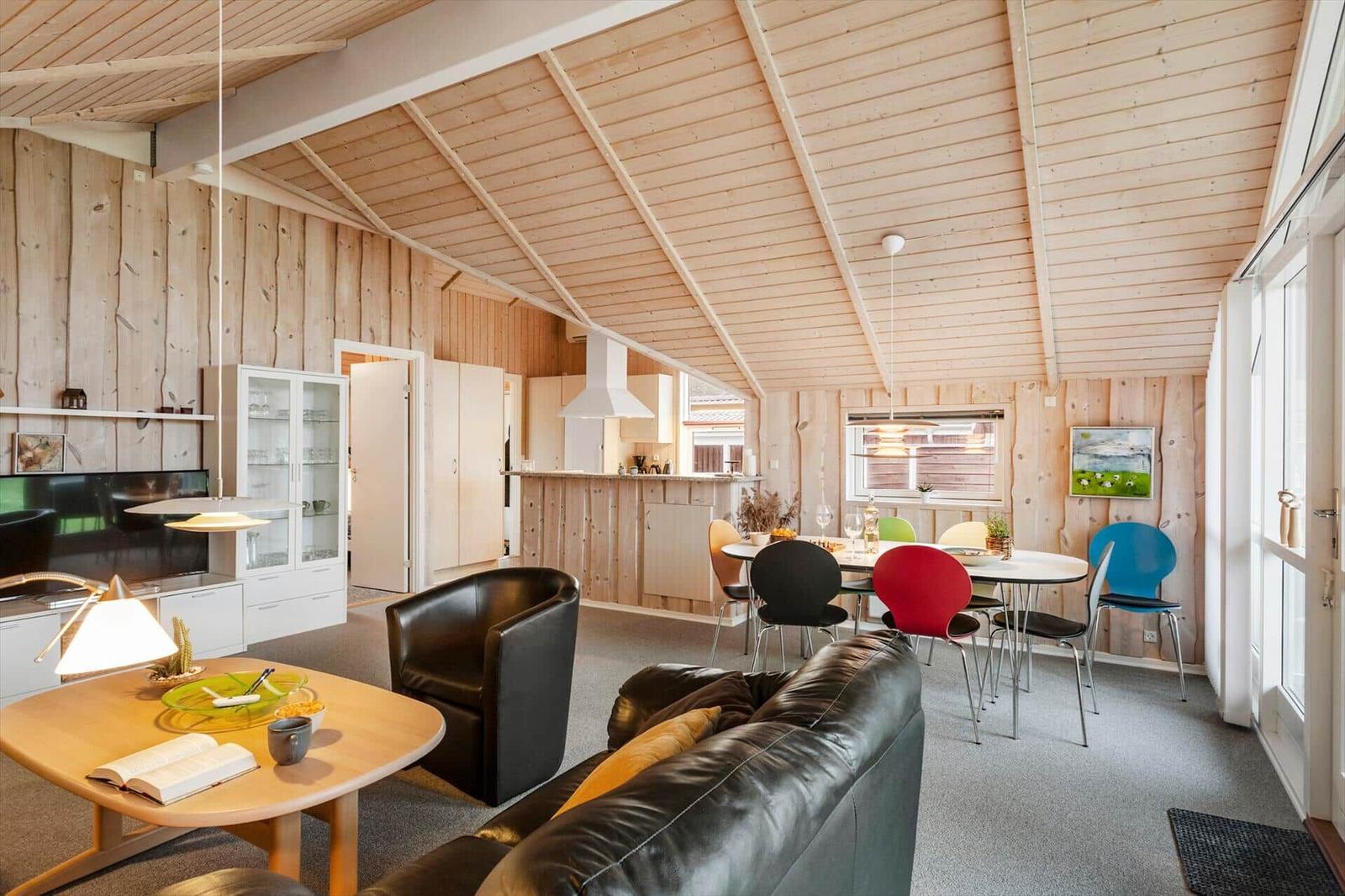 Wohn- und Essbereich mit Holzwand, Sofa, Tisch und Stühlen.