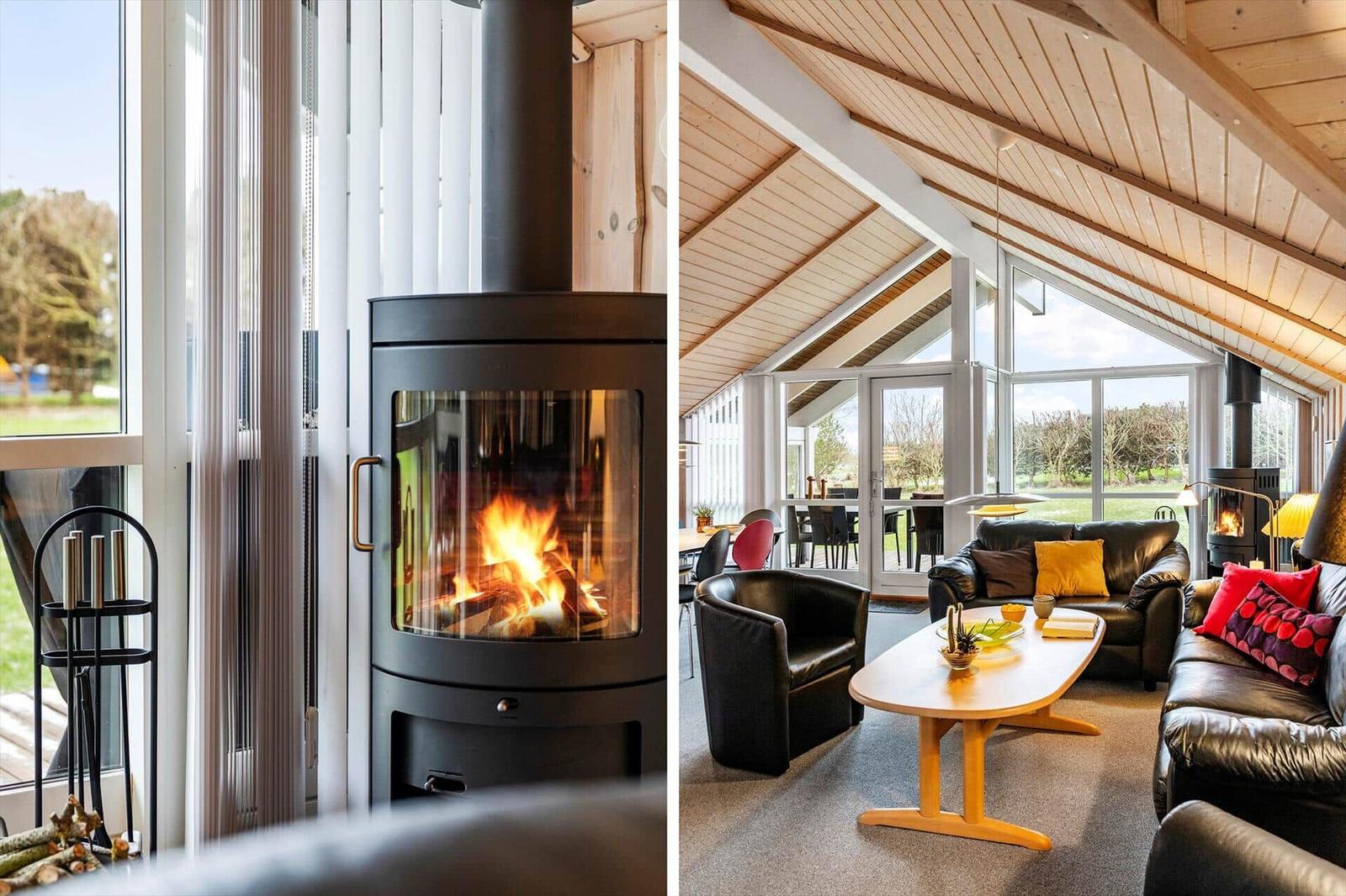 Wohnzimmer mit Kamin, Ledersofa und Holztisch. Große Fenster und Holzdecke.