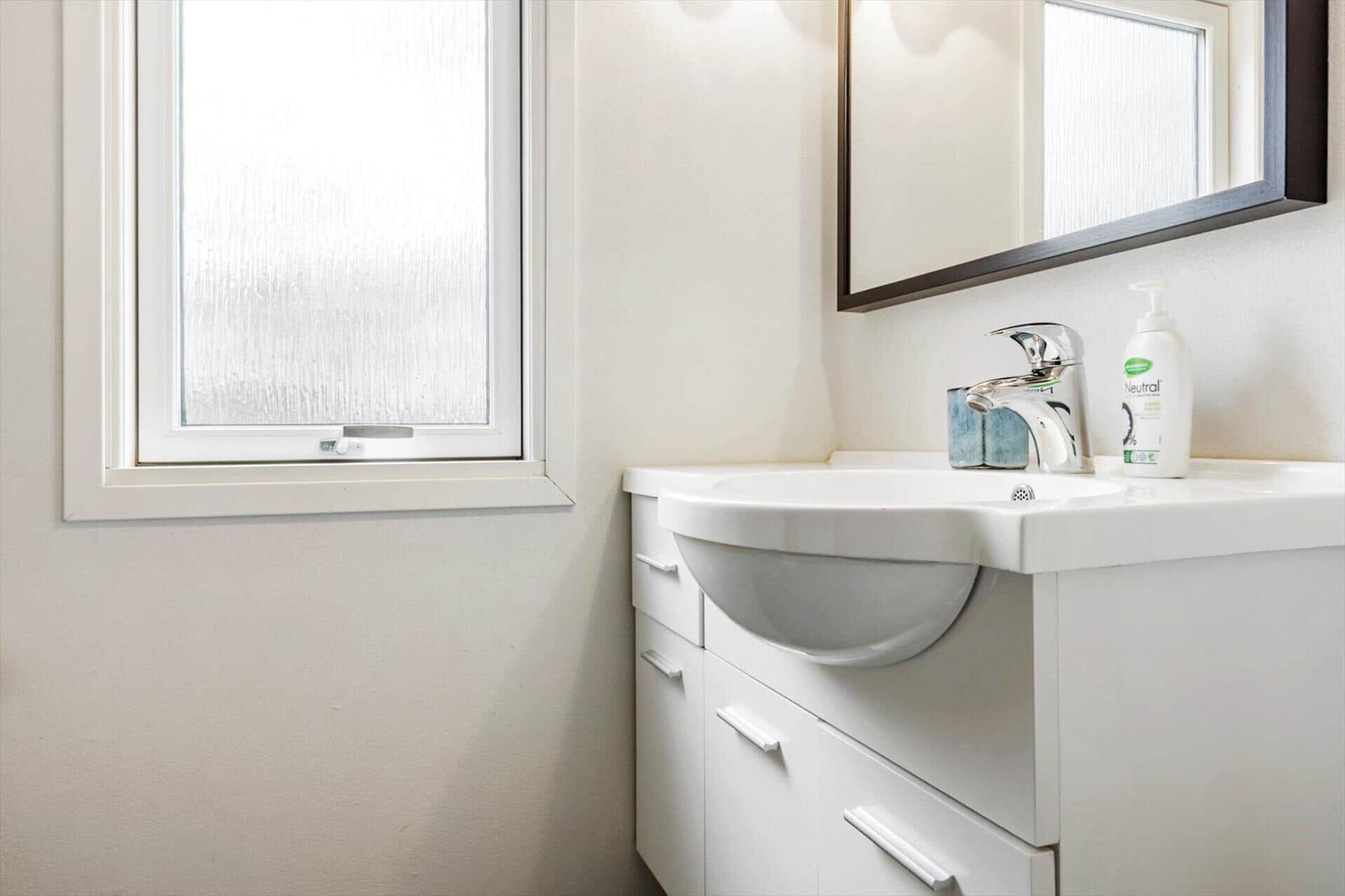 Waschbecken mit Spiegel und Fenster im Badezimmer