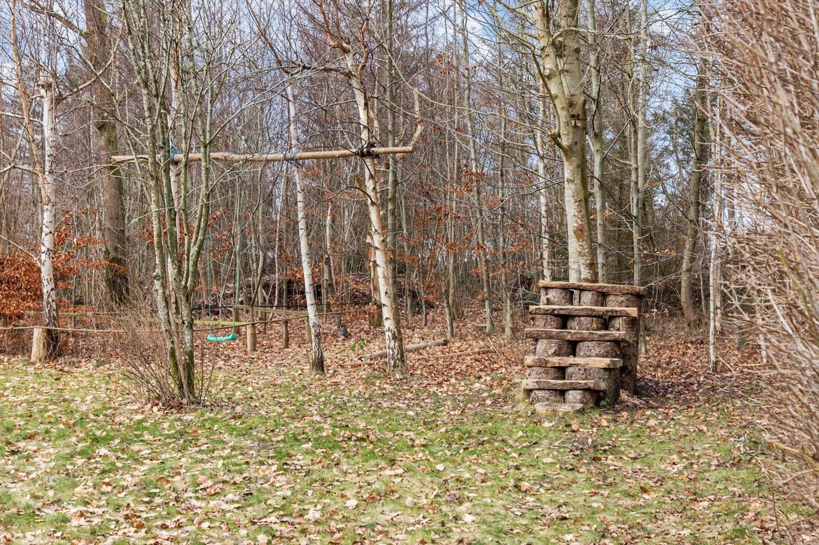 Holzspielplatz im Wald mit Schaukel und Klettergerüst.