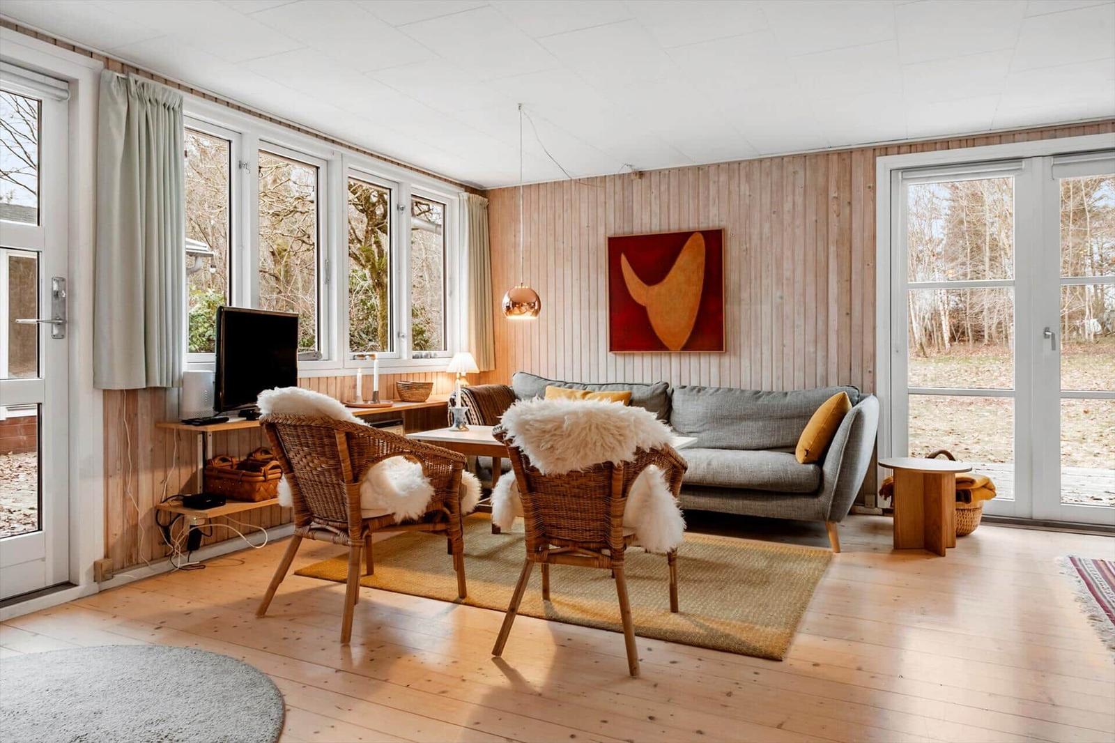 Wohnzimmer mit Sofa, zwei Stühlen und Fenstern zur Außenseite.