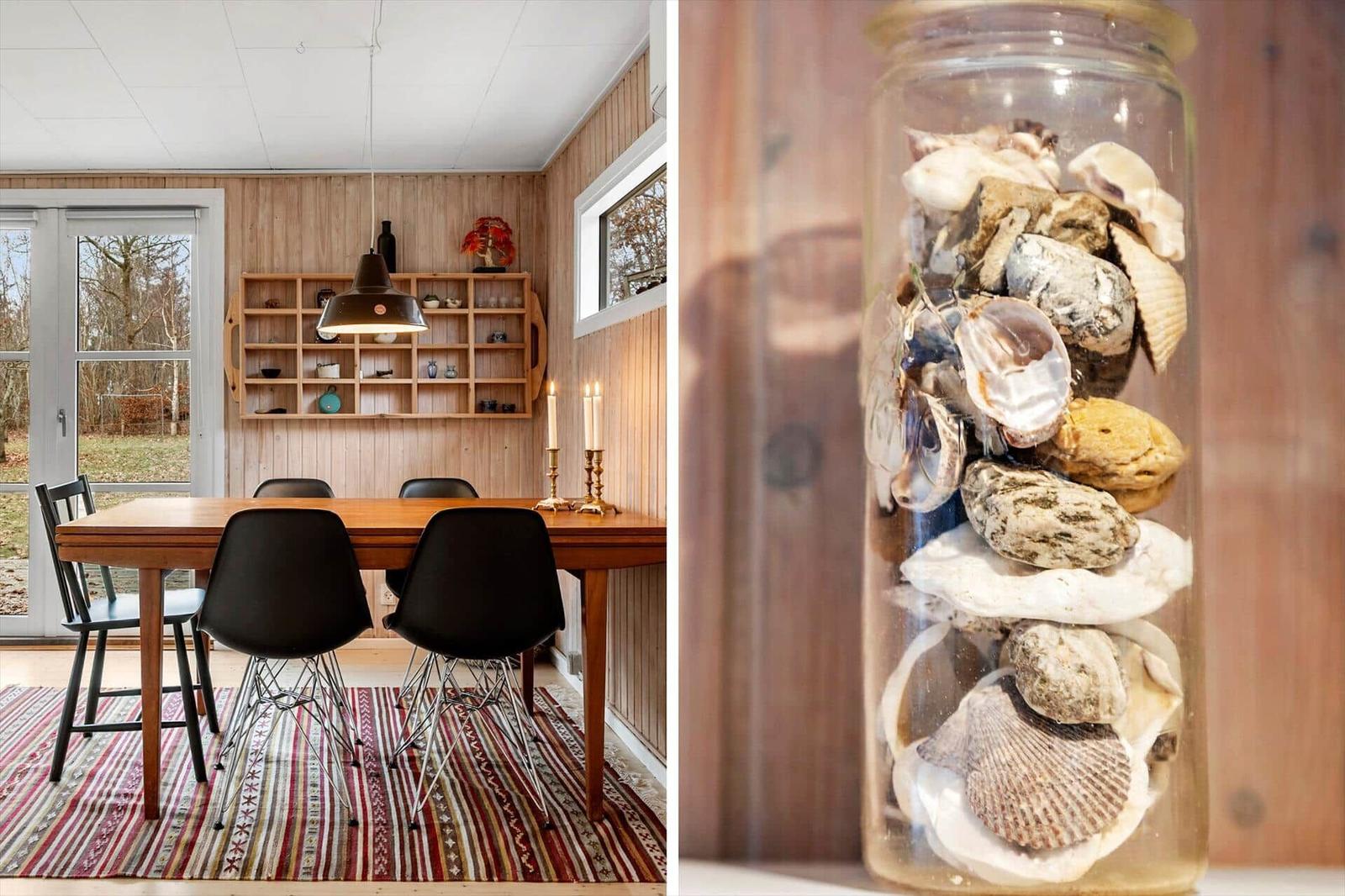 Esszimmer mit Holzwand und Tisch. Glasflasche mit Muscheln.