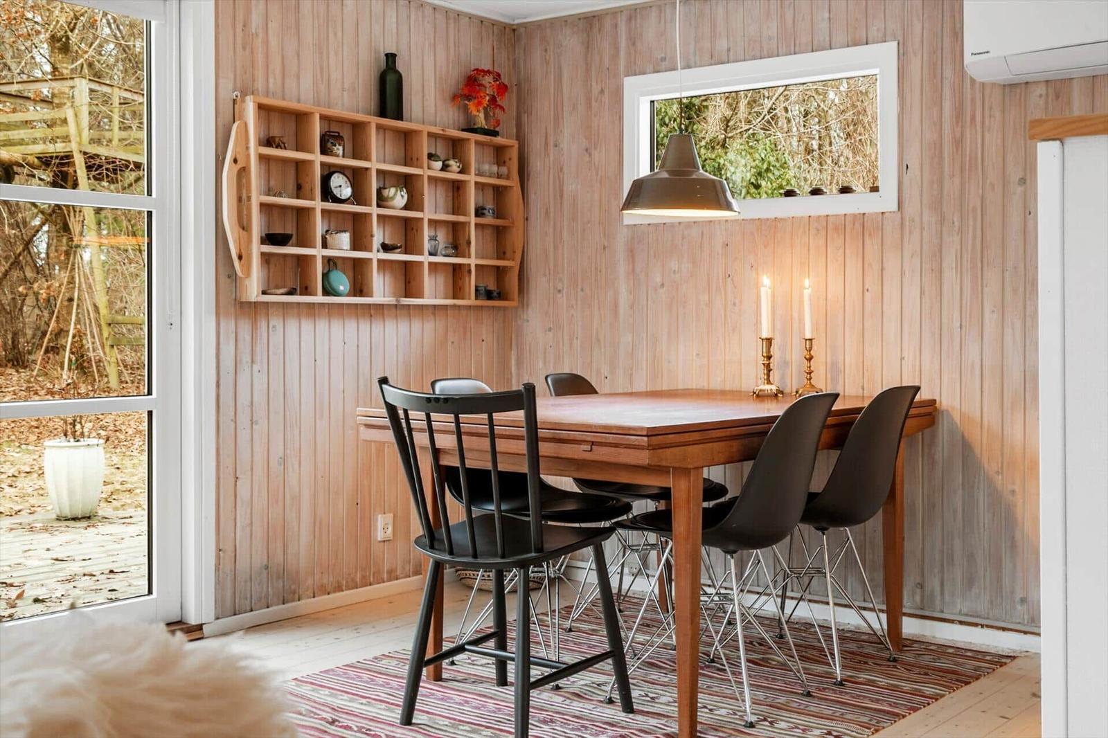 Esszimmer mit Holzwand, Tisch und Stühlen, Schrank und Fenster zur Außenseite.