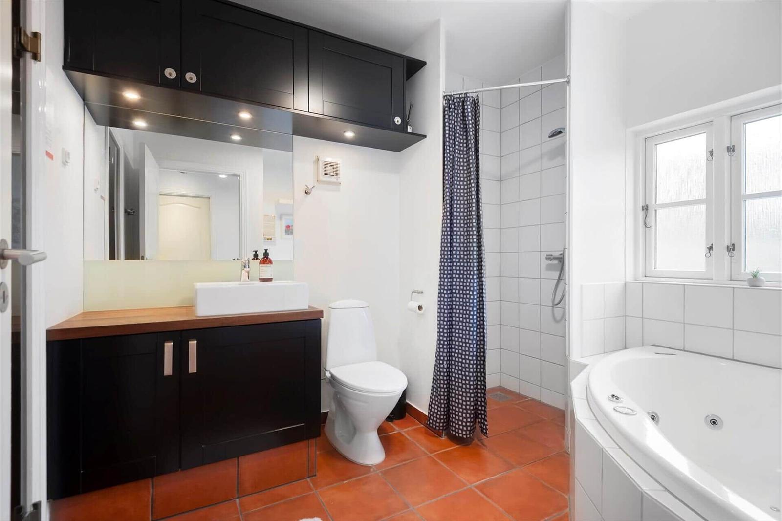 Bathroom with bathtub, shower, toilet, and sink with mirror.