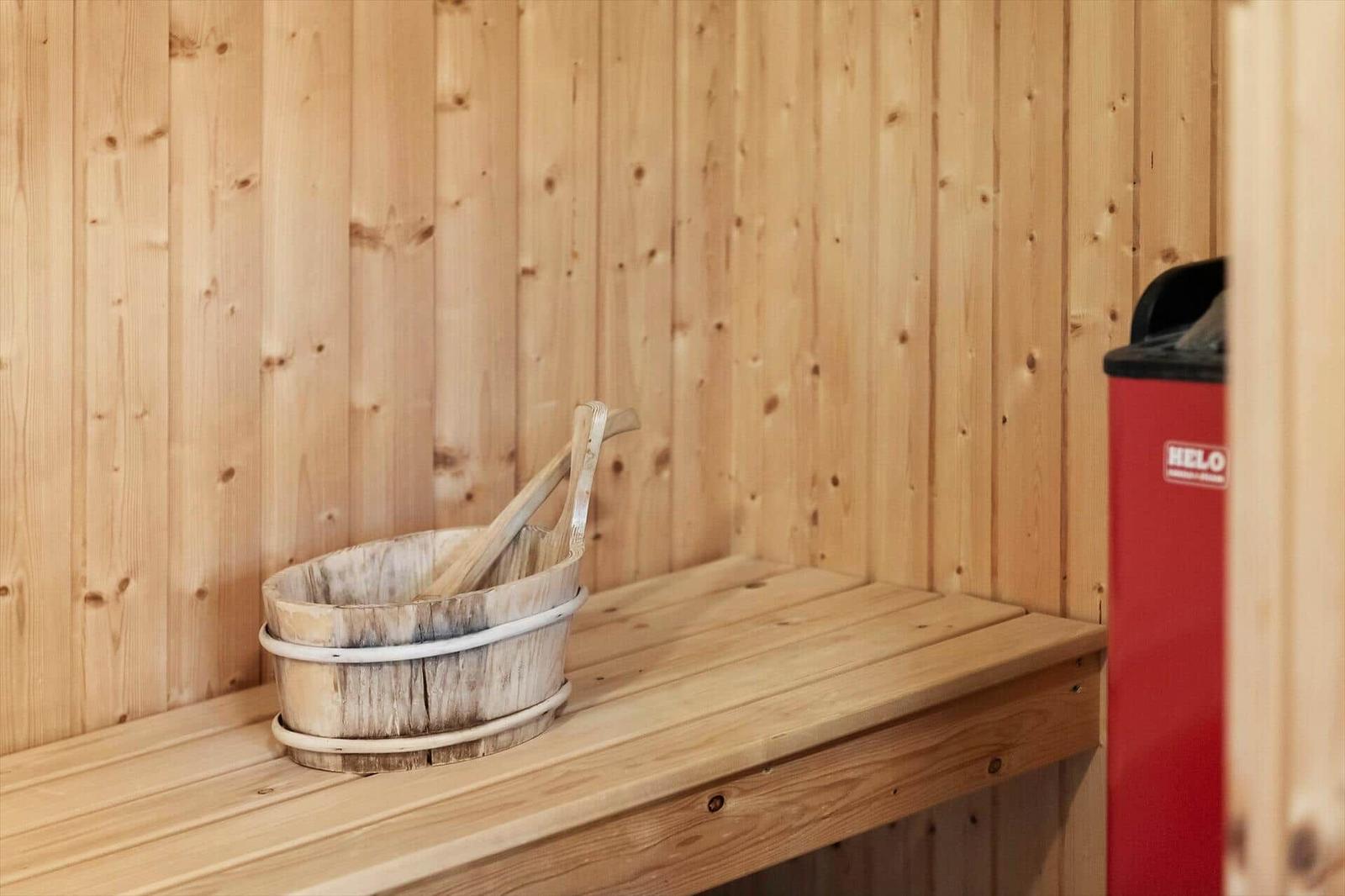 Wooden sauna with bucket and broom on bench