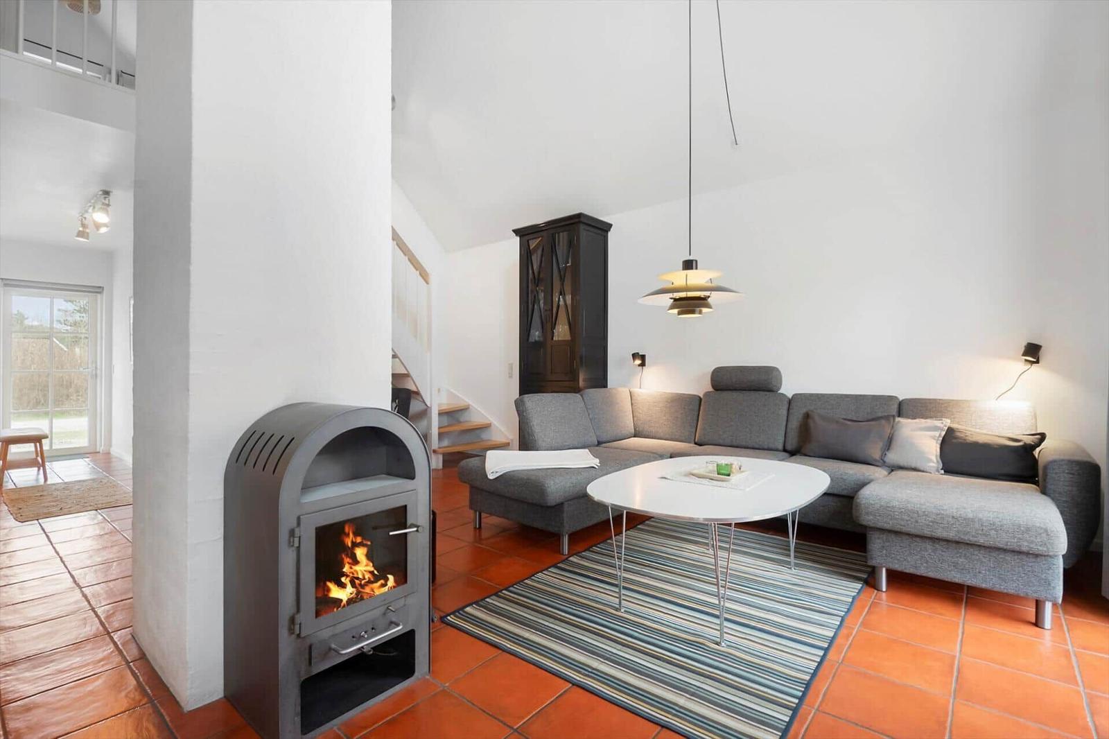 Living room with gray sofa, round table, and wood stove.