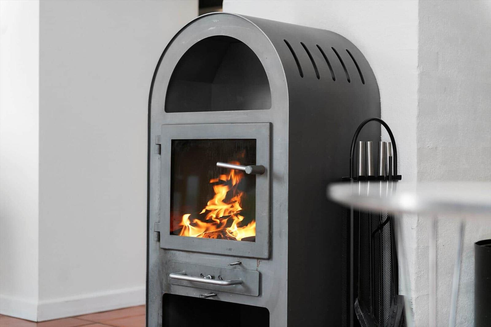 Modern fireplace with burning wood stove and metal handles.