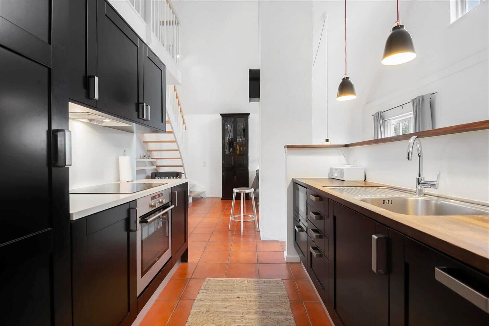 Kitchen with black cabinets, wooden countertop, and red tiles