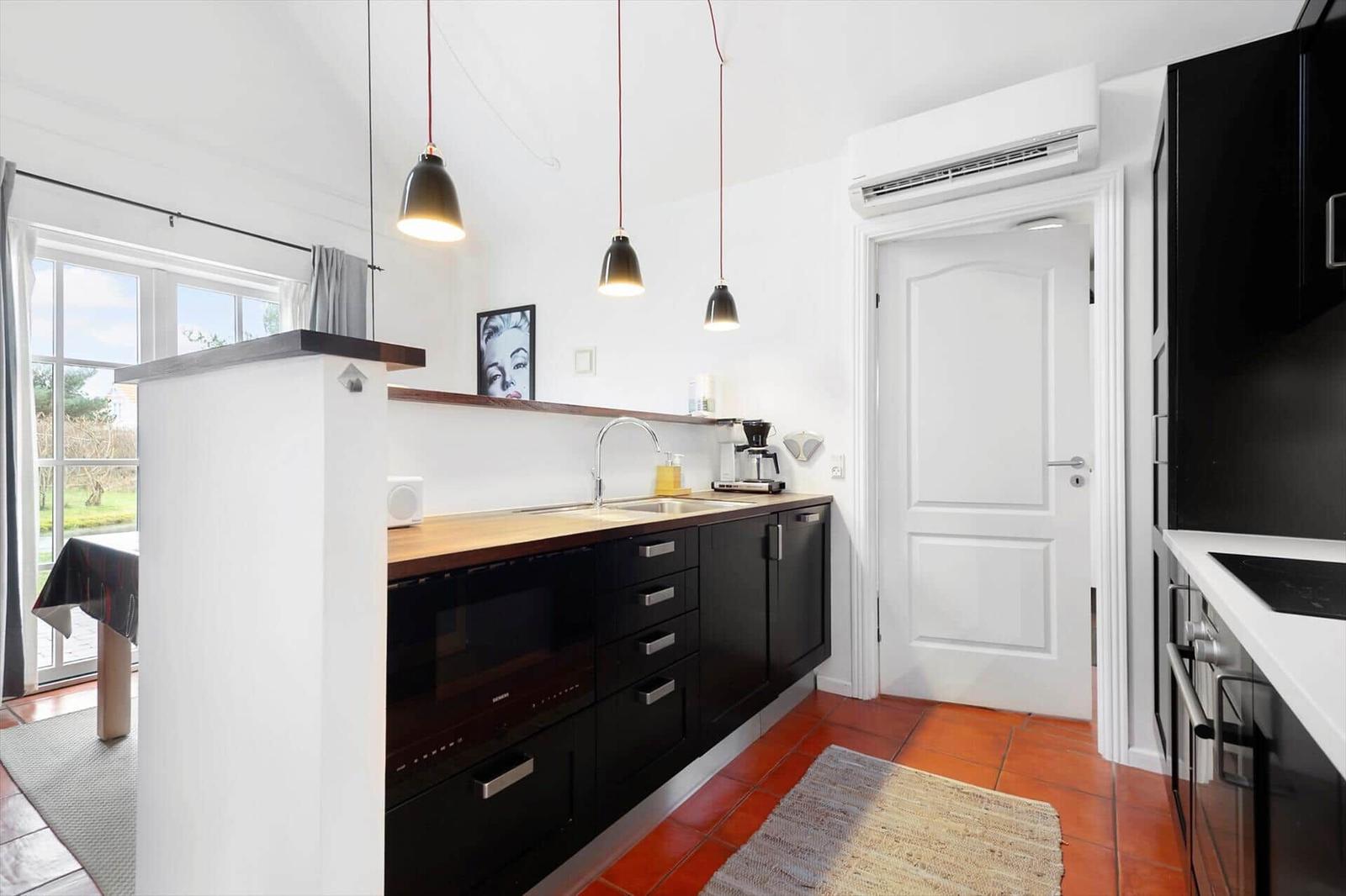Kitchen with black cabinets, wooden countertop, and red tiles.