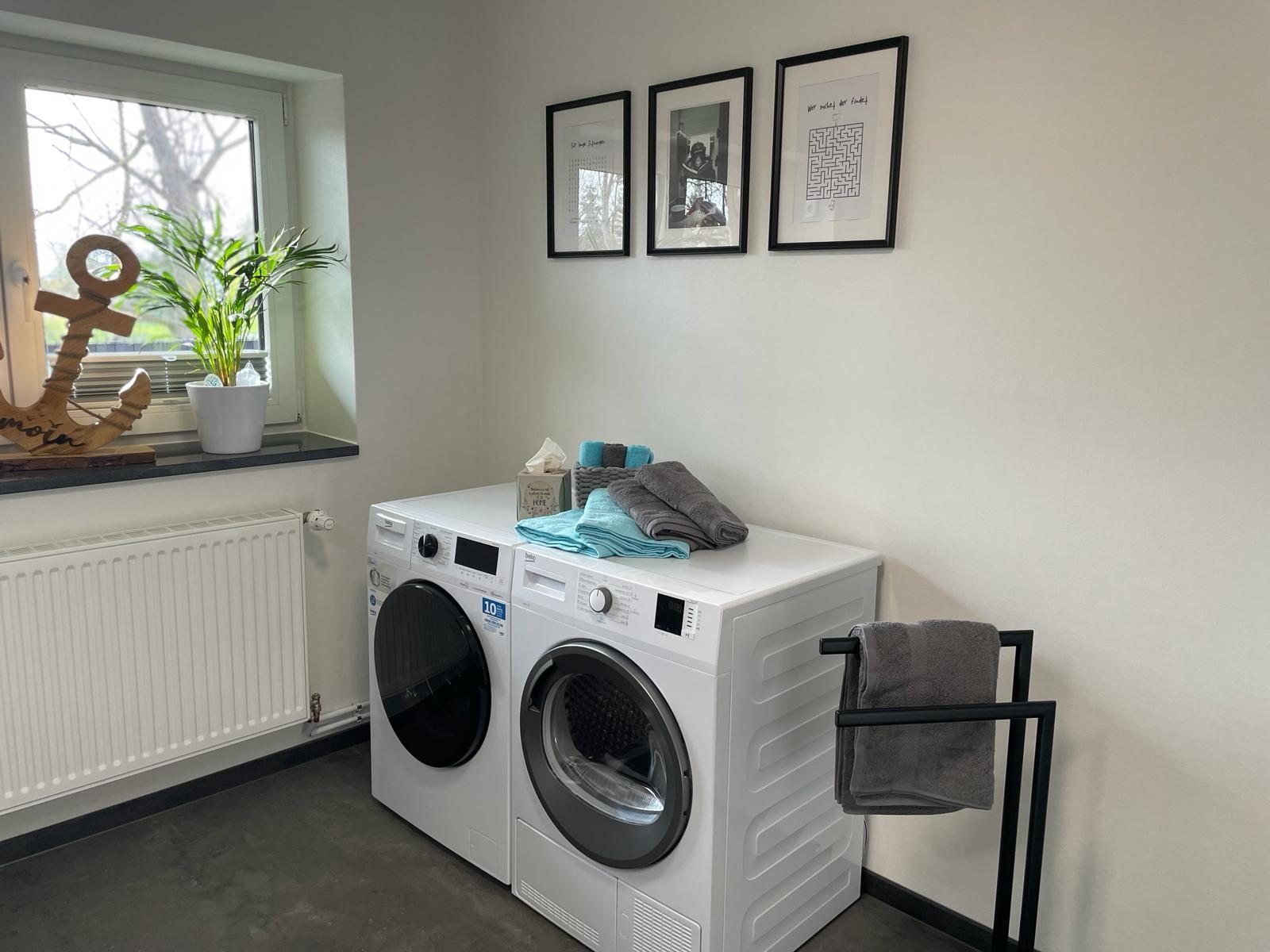 Wäscherei mit Waschmaschine und Trockner, Fenster mit Pflanze und Dekoration.