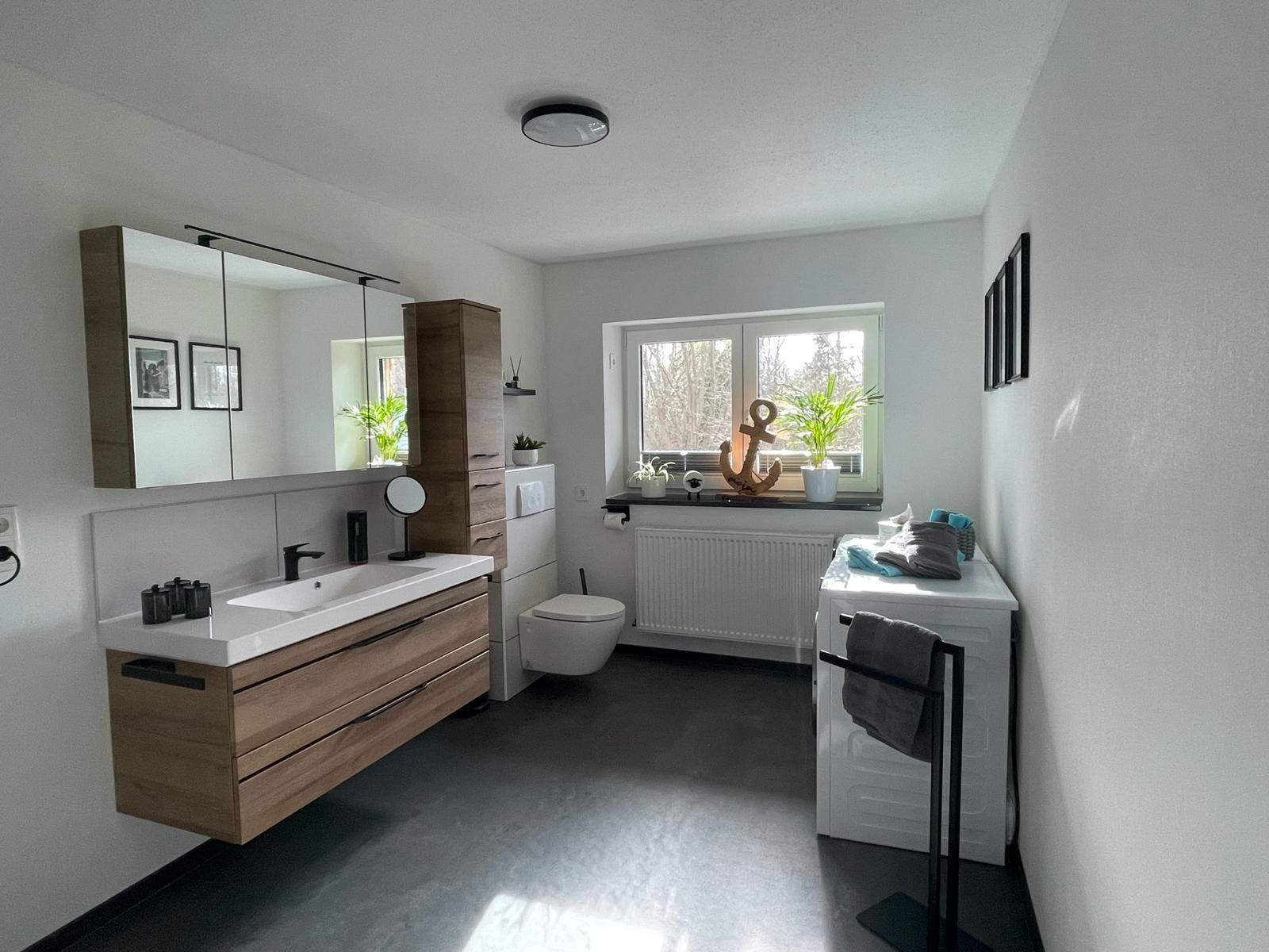 Bad mit Waschtisch, Spiegel und Fenster. Anker und Pflanzen auf Fensterbank.