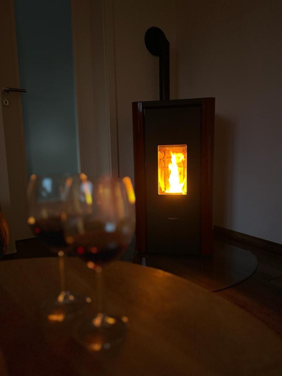 Im Wohnbereich brennt ein Kaminofen, vor ihm stehen zwei Weingläser auf einem Tisch.