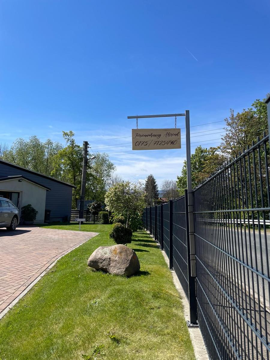 Ferienwohnung Ahrend mit Schild, Zaun und gepflastertem Weg.