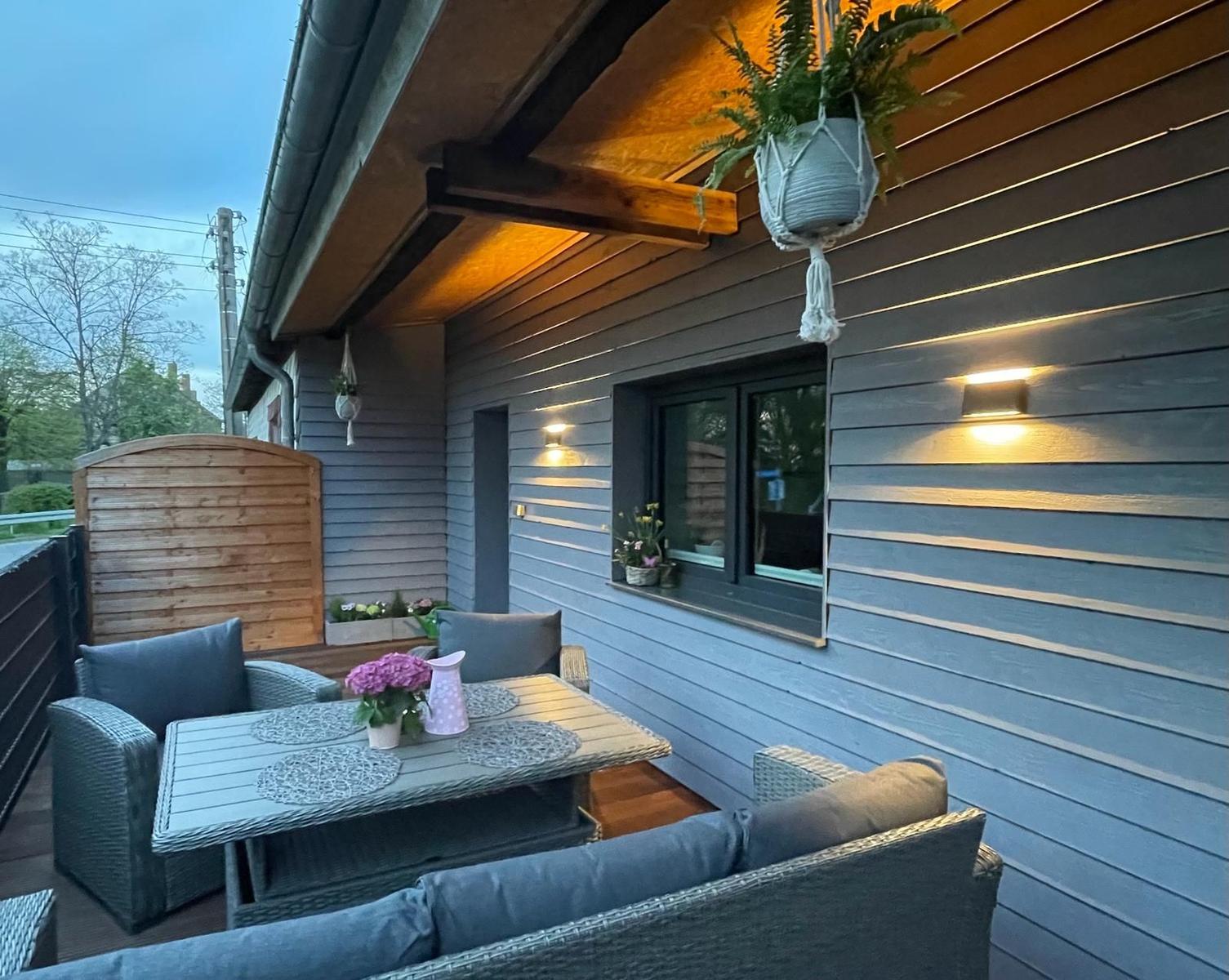 Terrasse mit Sitzgruppe, Tisch und Pflanzen unter Holzüberdachung.