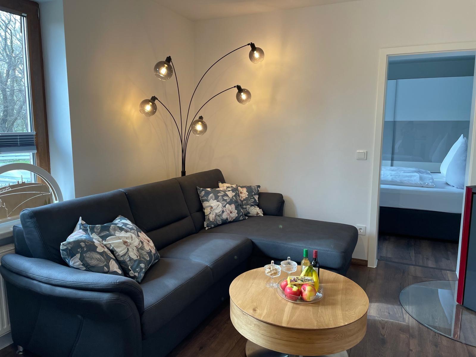 Wohnzimmer mit Sofa, Couchtisch und Lichterkette. Blick in Schlafzimmer.