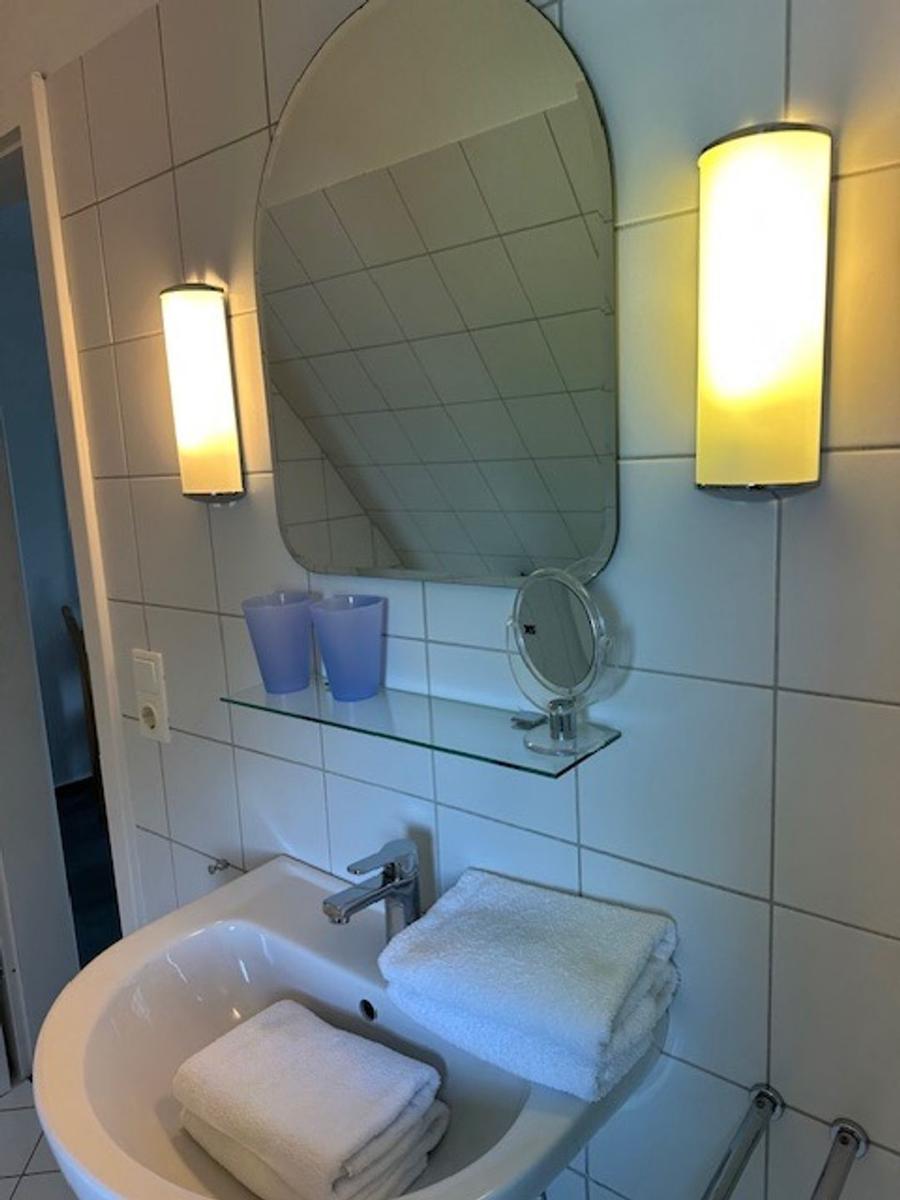 Badezimmer mit Waschbecken, Spiegel und Handtüchern