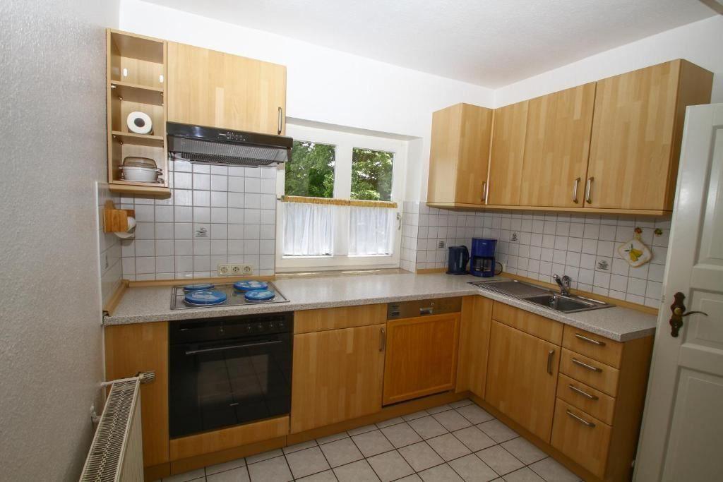 Küche mit Holzschränken, Kochfeld und Fenster.