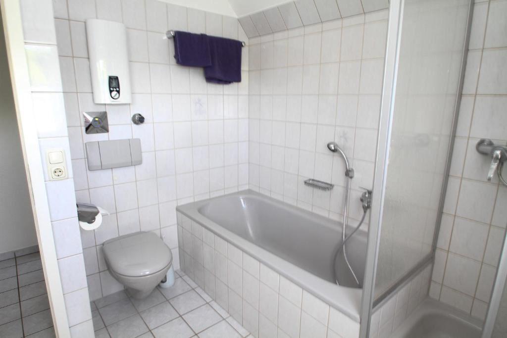 Badezimmer mit Badewanne, Dusche, WC und Heizung.