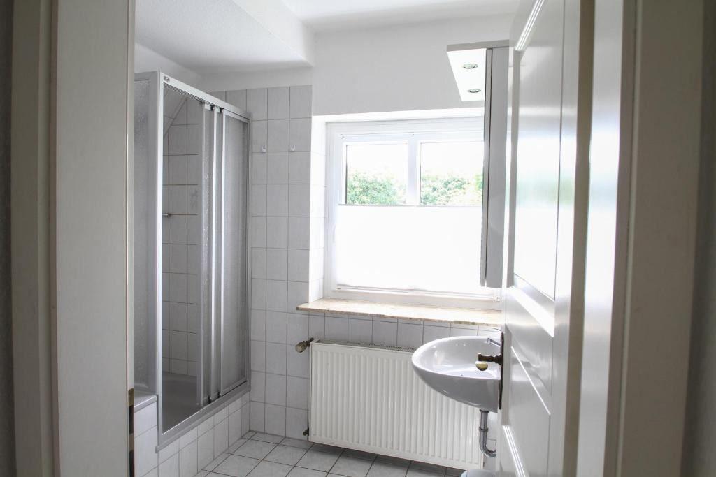 Badezimmer mit Dusche, Waschbecken und Fenster.