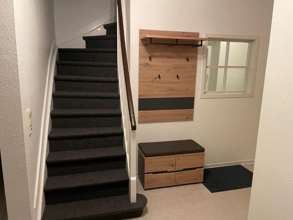 Treppe mit Holzgeländer, Wandregal und Sitzbank im Eingangsbereich.