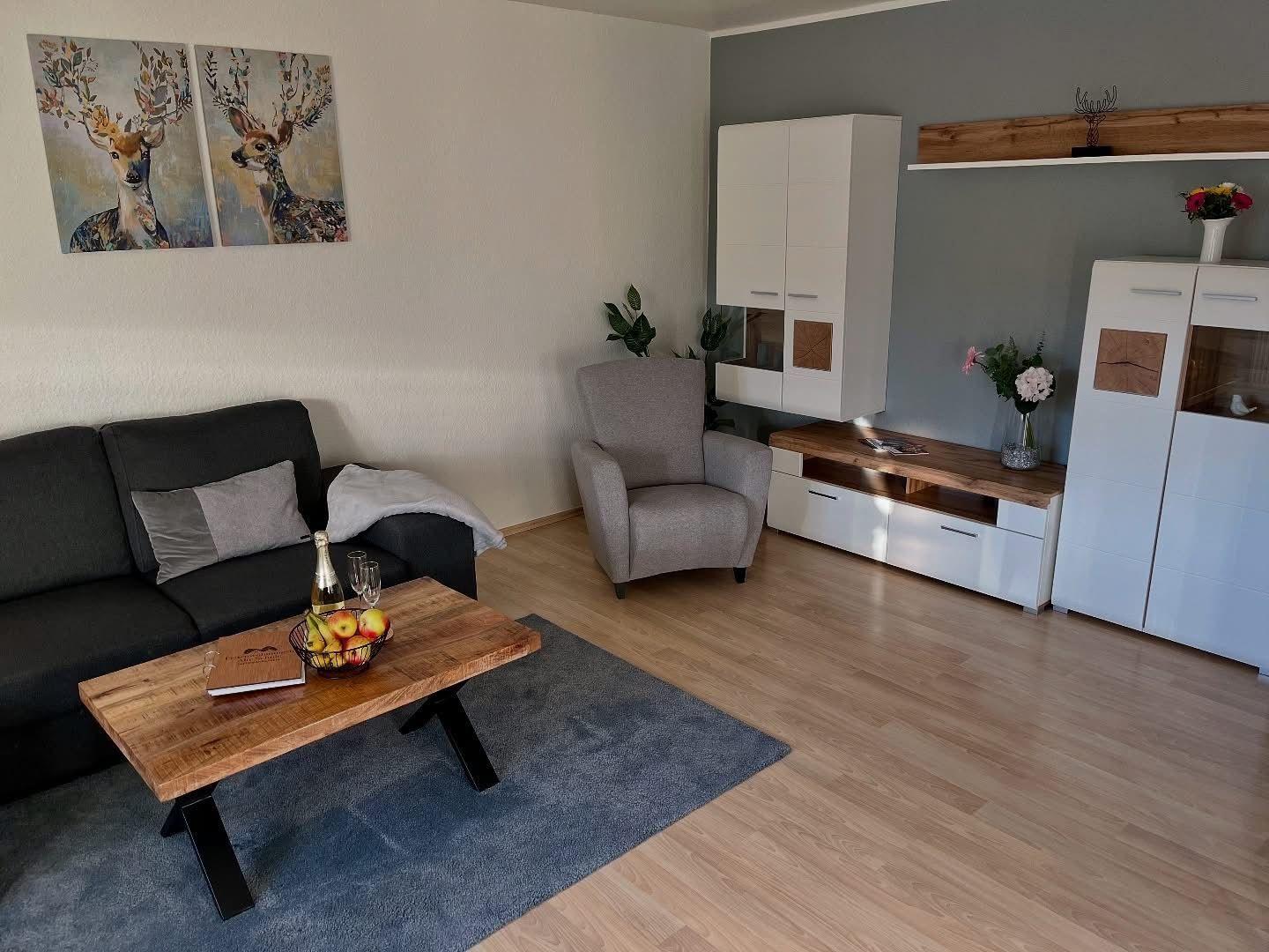 Wohnzimmer mit Sofa, Sessel, Couchtisch und Wandbildern