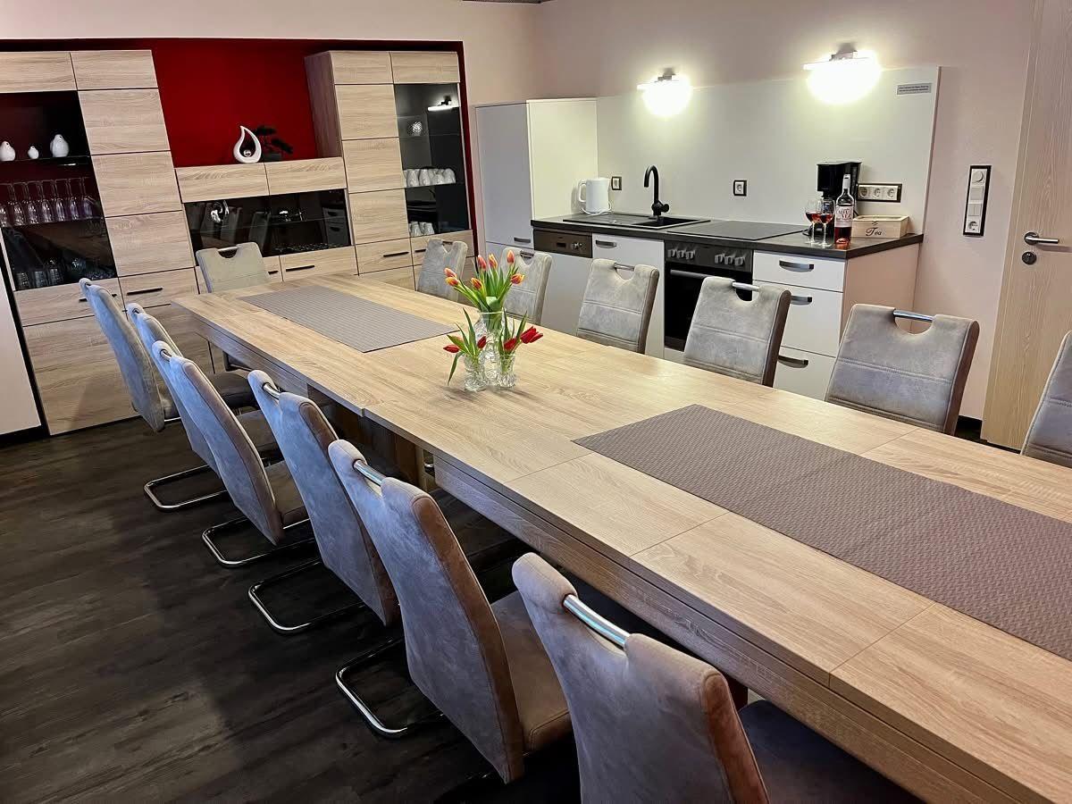 Langtisch mit acht Stühlen, Küchenbereich und Speisekammer im Hintergrund.