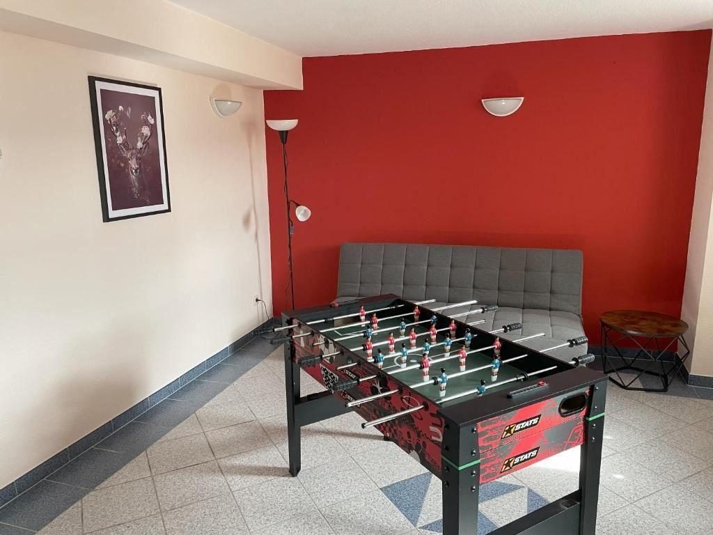 Fußballtisch mit grauem Sofa und roter Wand