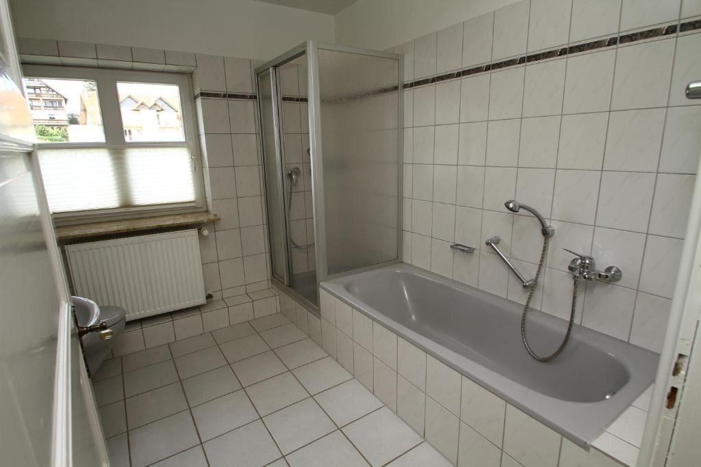 Badezimmer mit Badewanne, Dusche und Fenster.