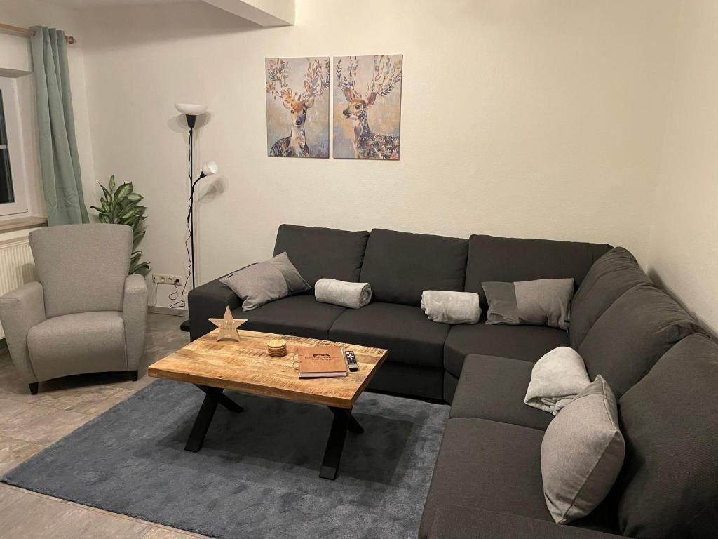 Wohnzimmer mit Ecksofa, Holztisch und Wandbildern mit Hirschen.