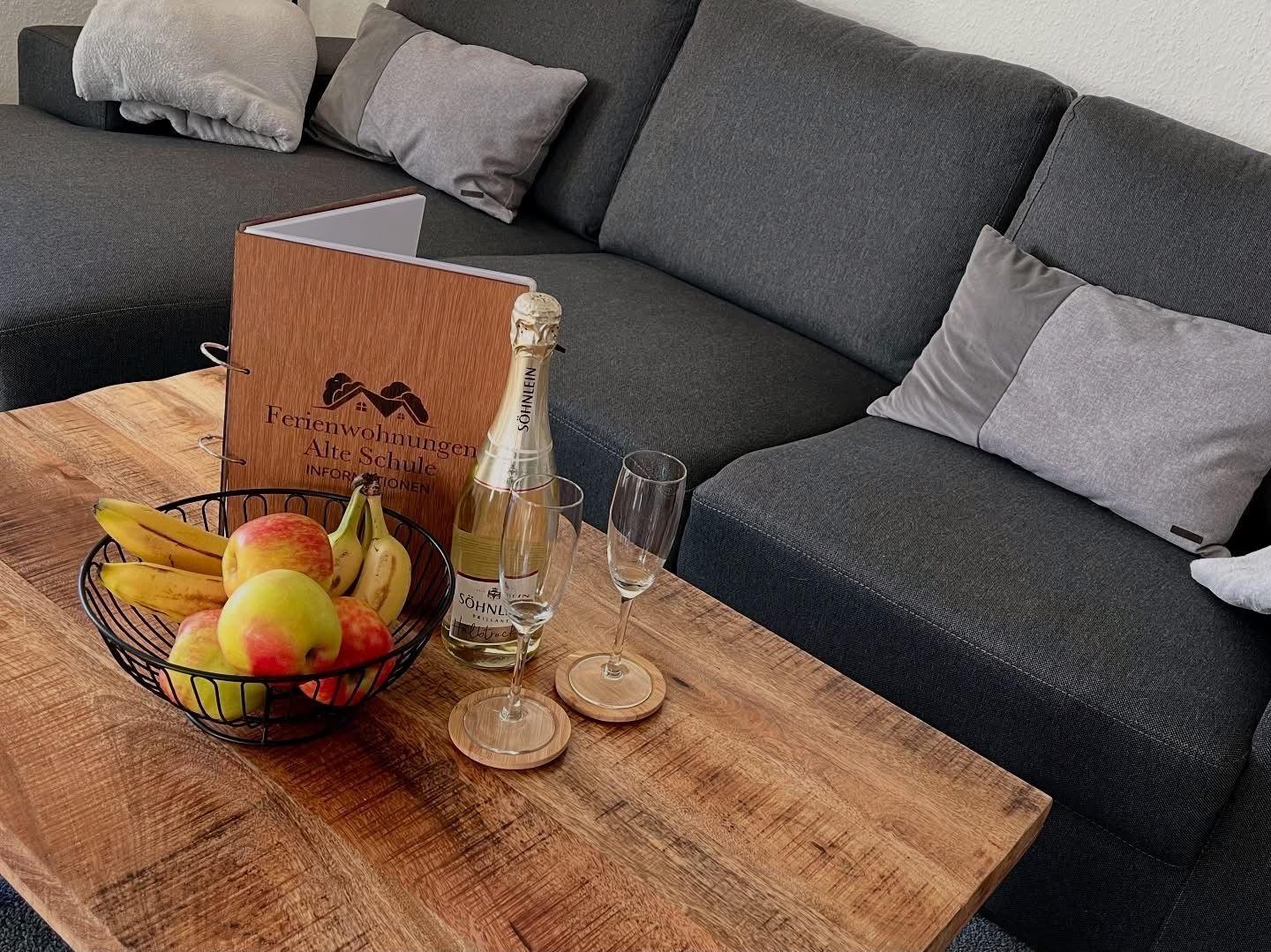 Holztisch mit Obstschale, Champagner und Kissen auf Sofa