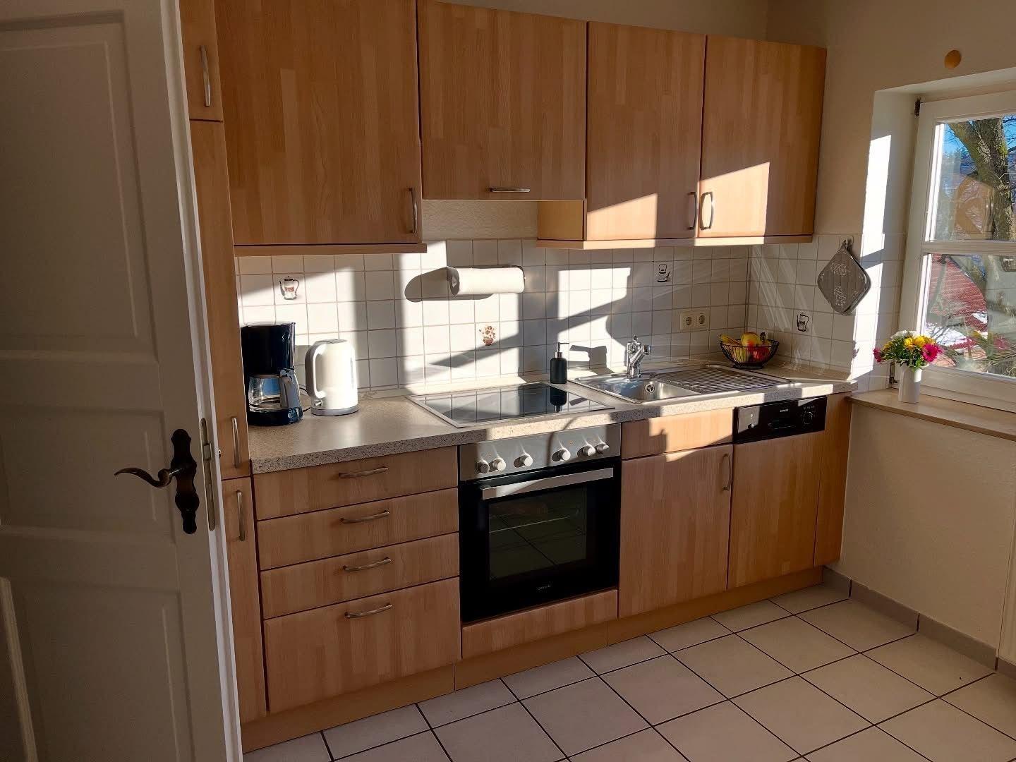 Küche mit Holzschränken, Spüle und Fenster