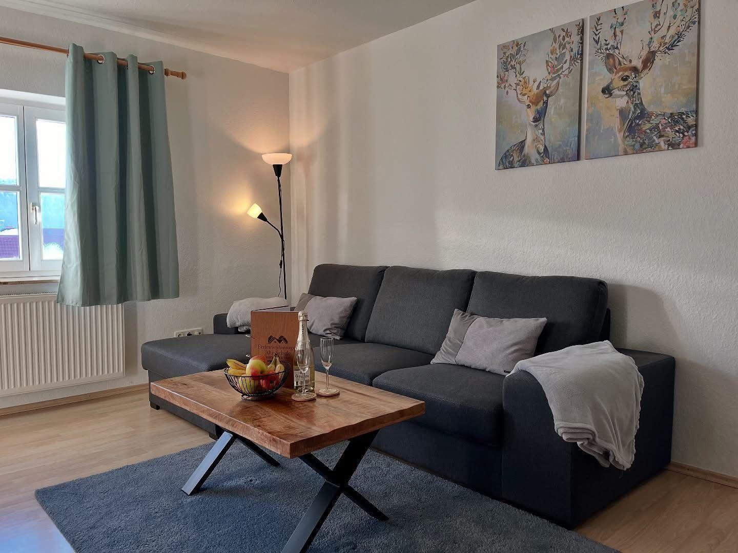 Ein Wohnzimmer mit Sofa, Tisch und Wandbildern