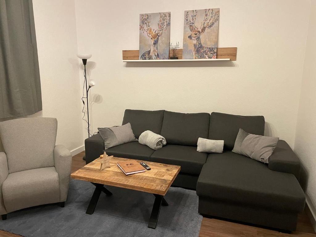 Ein Wohnzimmer mit grauem Sofa, Holztisch und Wandbildern von Hirschen.