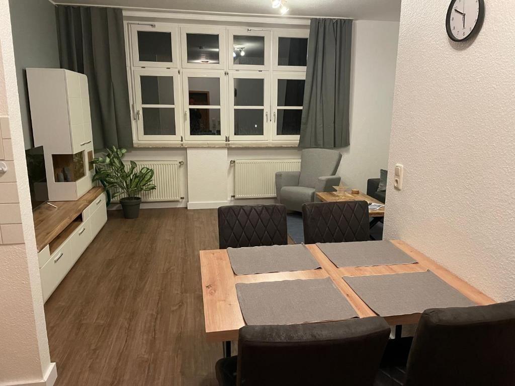Esszimmer mit Tisch und Stühlen, dahinter Wohnbereich mit Fenster und Sessel.
