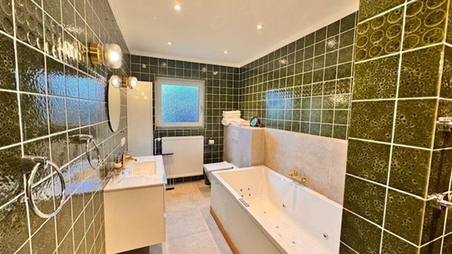 Badezimmer mit Badewanne, Waschbecken und grünen Fliesen