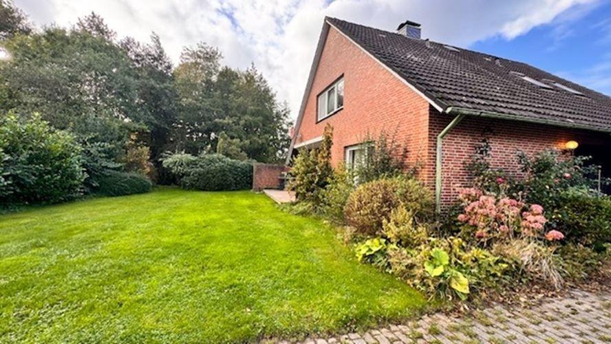 Rotes Backsteingebäude mit Garten und Blumenbeet. 