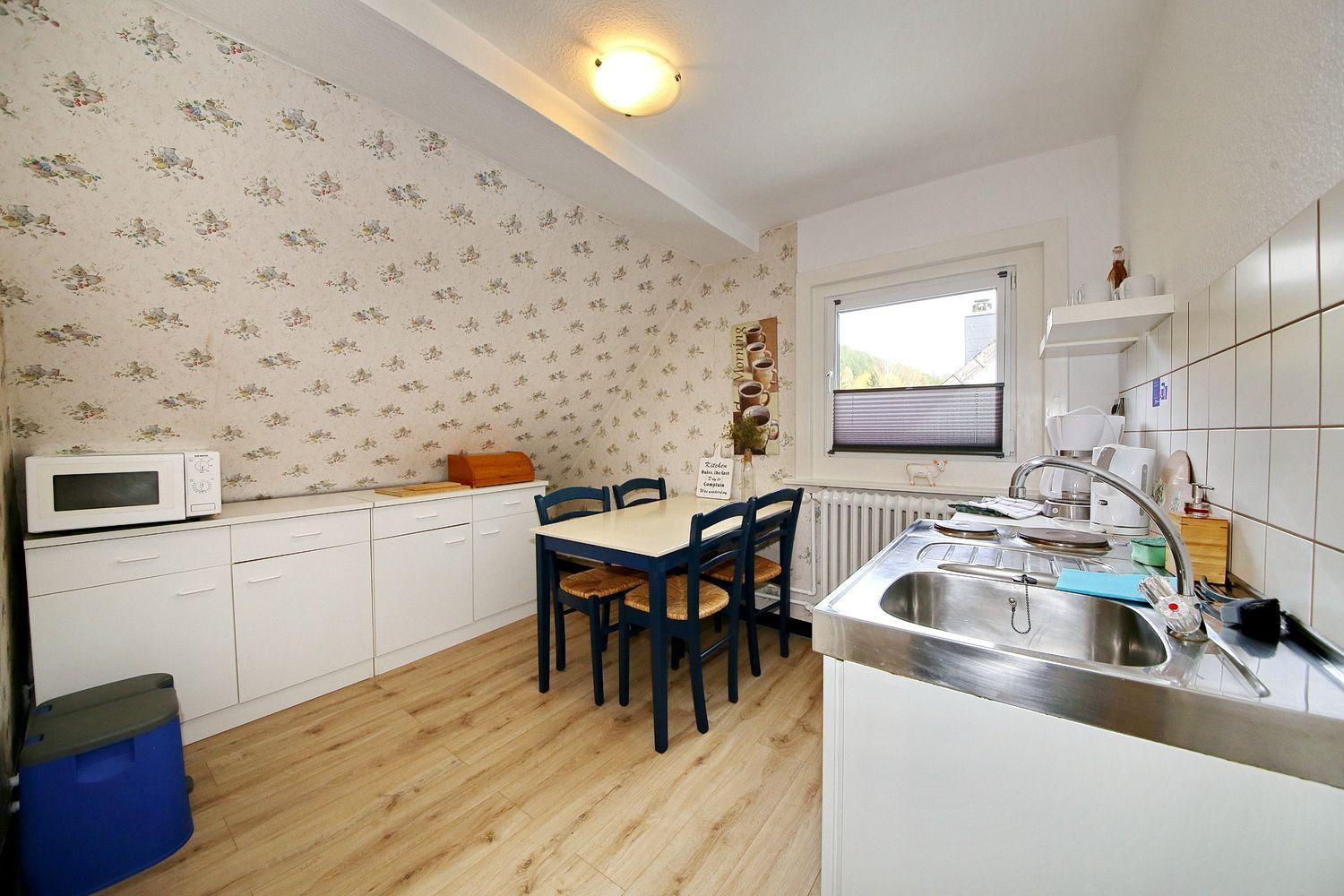 Küche mit Essbereich, Fenster, Spüle und Mikrowelle.