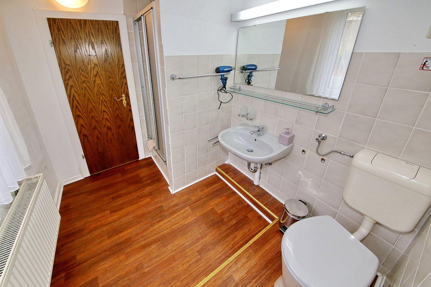 Badezimmer mit Dusche, Waschbecken, Toilette und Haartrockner.