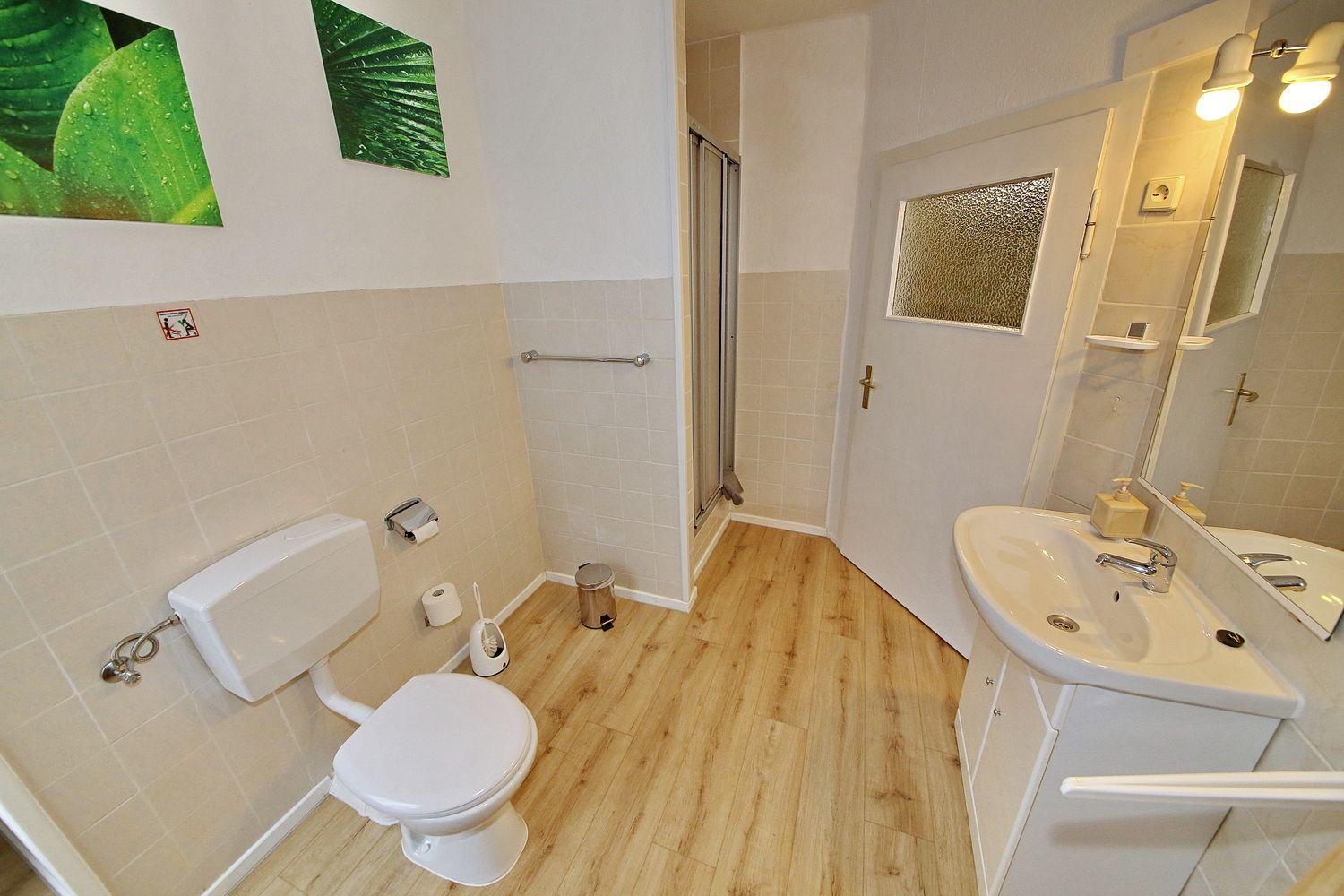 Badezimmer mit Toilette, Dusche und Waschbecken auf Holzfußboden.