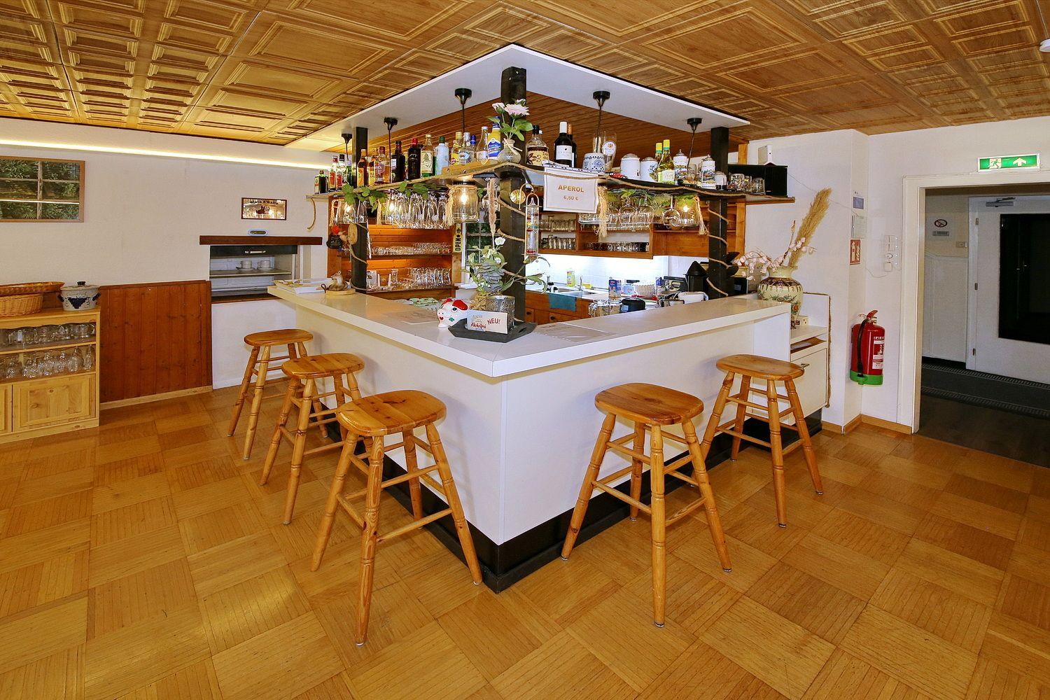 Barbereich mit Holzstühlen und Flaschenregal