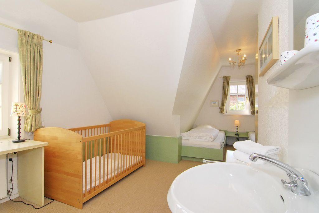 Schlafzimmer mit Kinderbett, kleinem Bett und Waschbecken