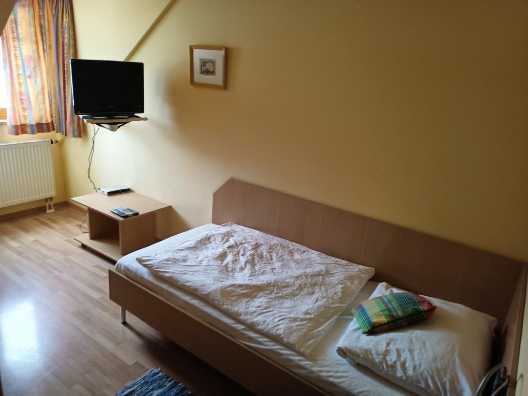 Ein Schlafzimmer mit Bett, Fernseher und Holzboden.