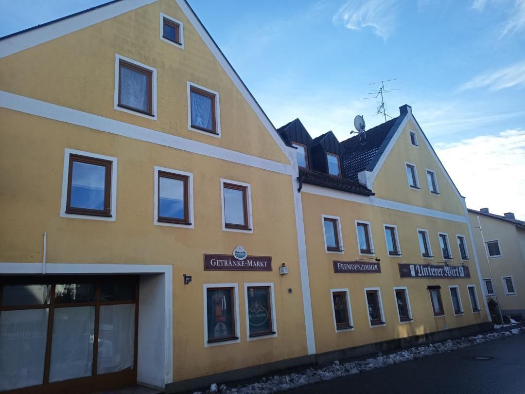 Gelbes Gebäude mit Fenstern und Schildern wie Getränke-Markt und Fremdenzimmer.
