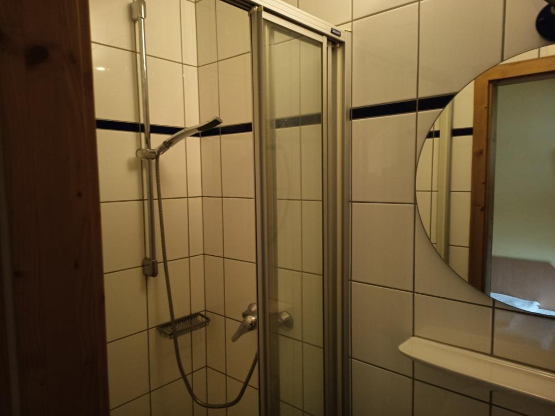 Badezimmer mit Duschkabine, Spiegel und Waschbecken