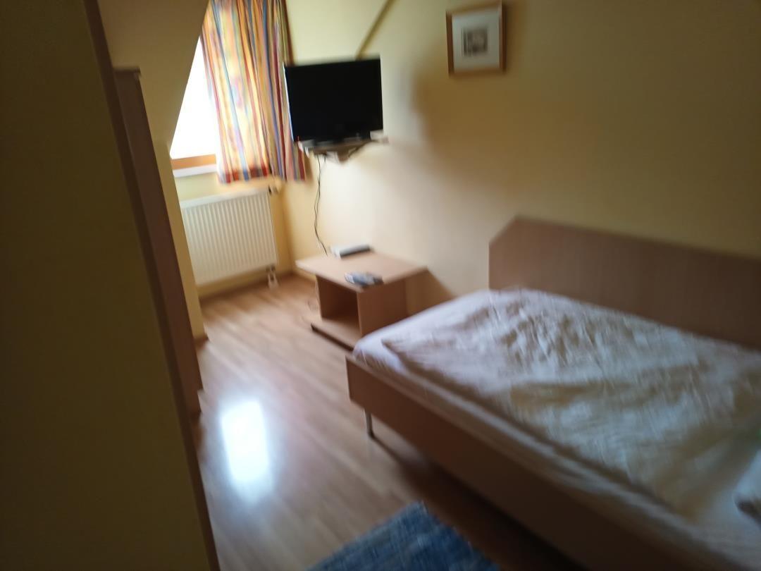 Schlafzimmer mit Bett, Fernseher und Fenster