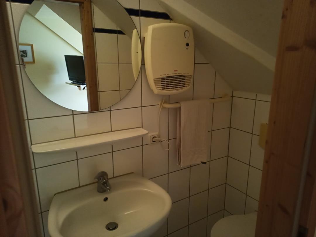Badezimmer mit Waschbecken, Spiegel und Heizung.