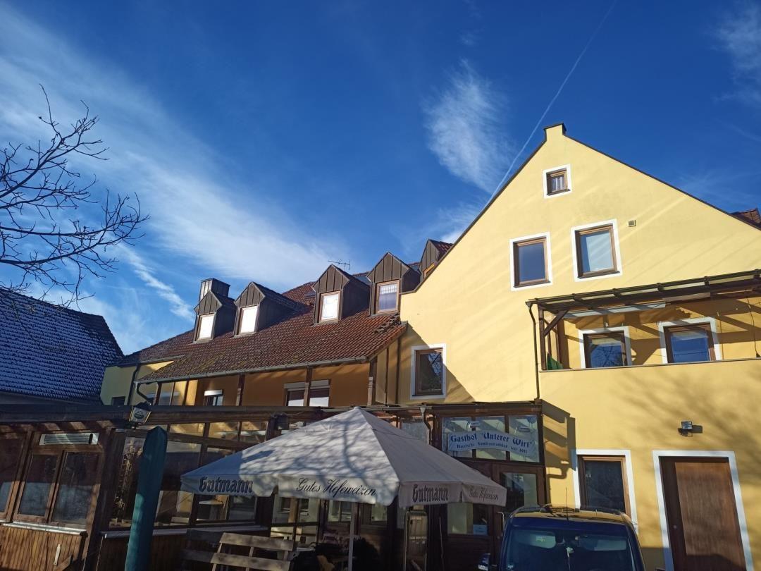 Gelbes Haus mit Dachgauben und Terrasse unter blauem Himmel.