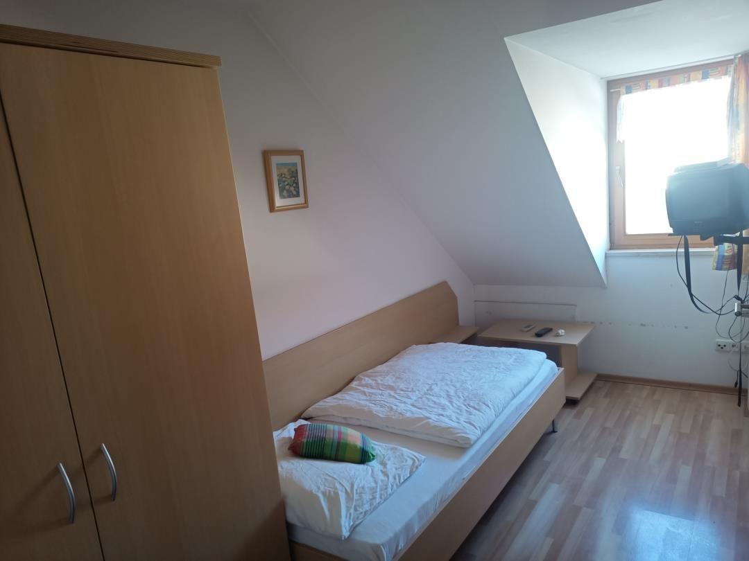 Schlafzimmer mit Dachschrägen, Bett, Kleiderschrank und Fenster.