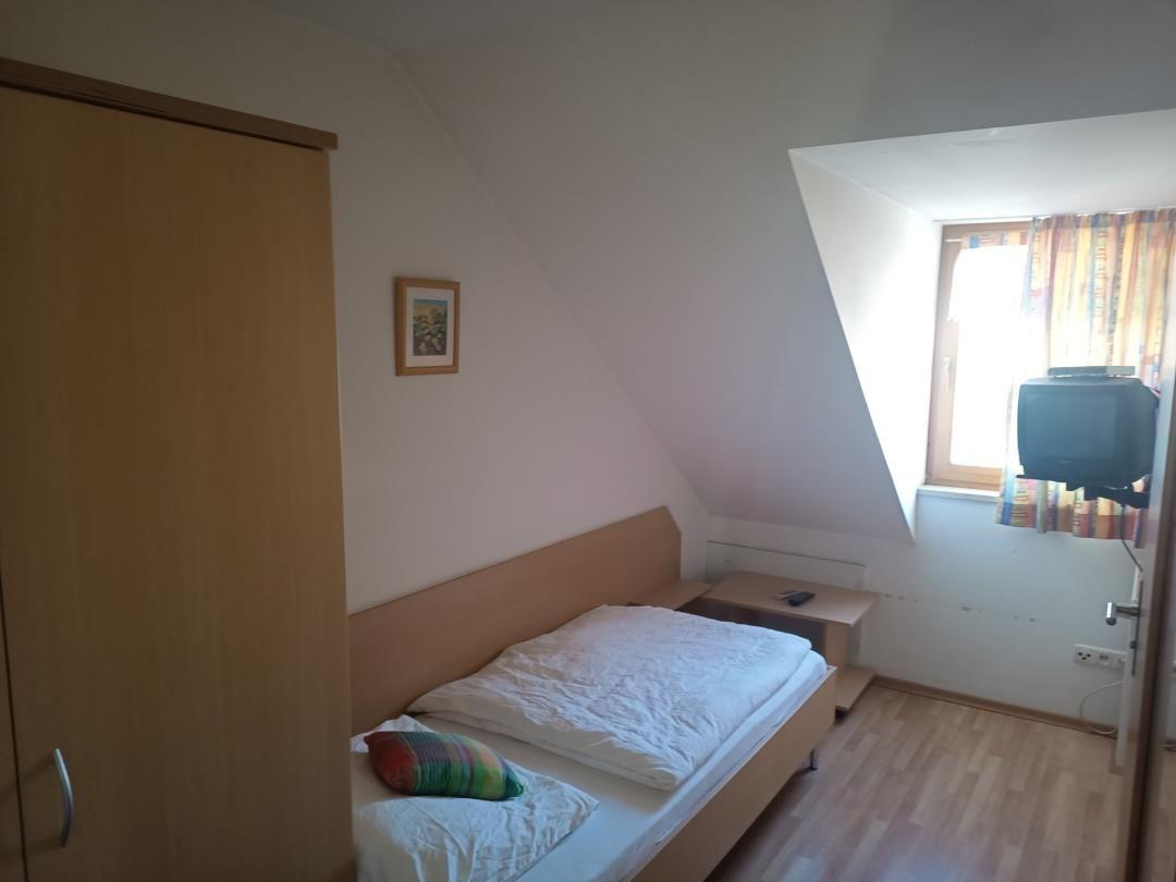 Schlafzimmer mit Dachschrägen, Bett, Kleiderschrank und Fernseher.