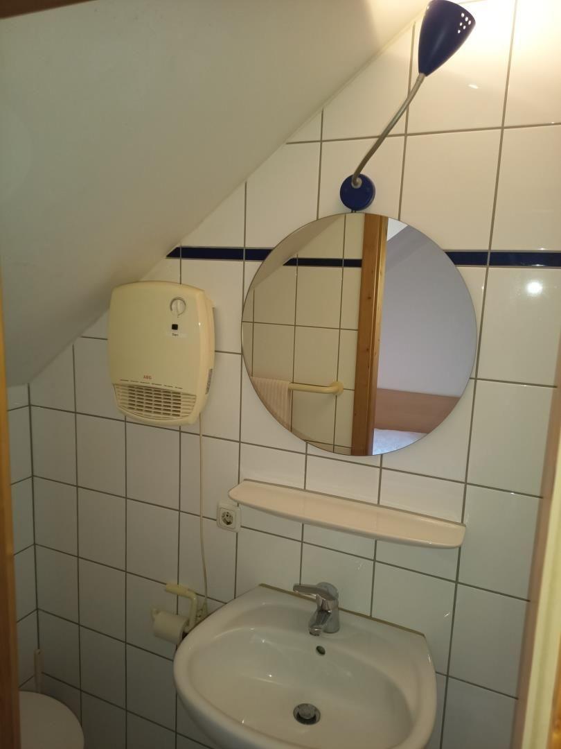Badezimmer mit Waschbecken, Spiegel und Heizung an geneigter Wand